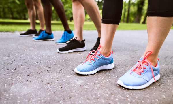 Close up of legs of young athletes prepared for run in green sunny summer park.