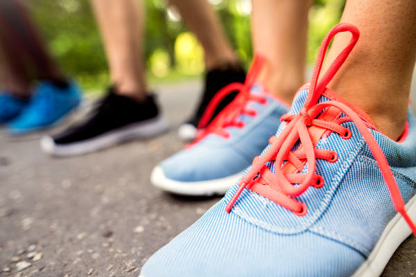 Close up of legs of young athletes prepared for run in green sunny summer park.