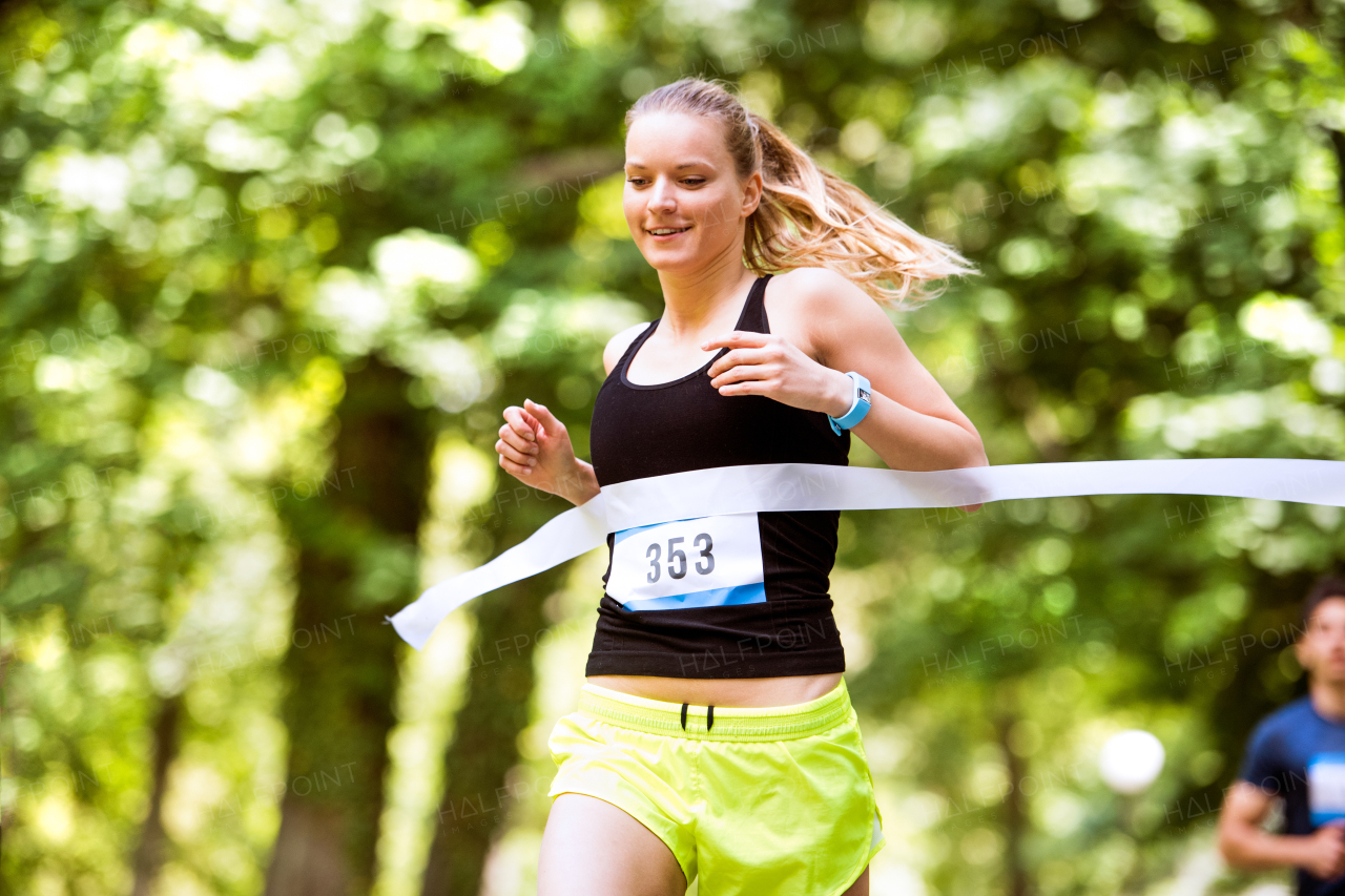 Beautiful young woman running the race crossing the finish line.