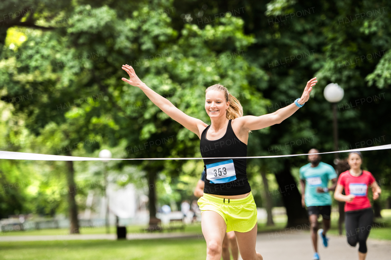 Beautiful young woman running in the crowd crossing the finish line.