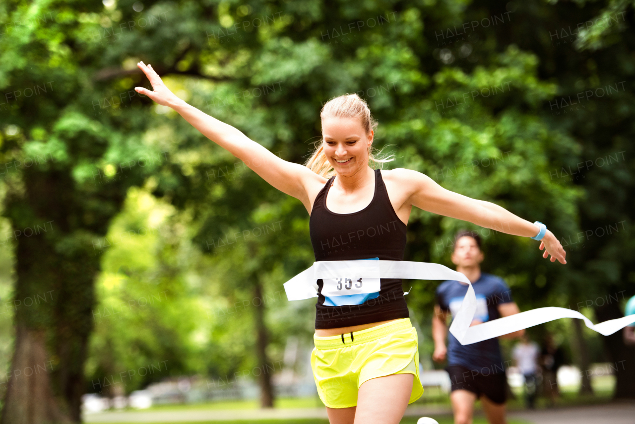 Beautiful young woman running in the crowd crossing the finish line.