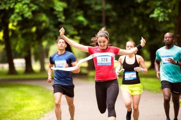 Beautiful young woman running in the crowd crossing the finish line.