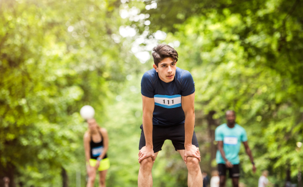 Young fit hispanic man with friends in park resting after finishing race.