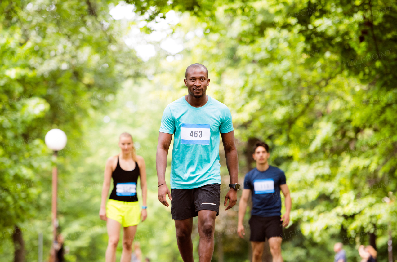 Group of young athletes prepared for run in green sunny summer park.