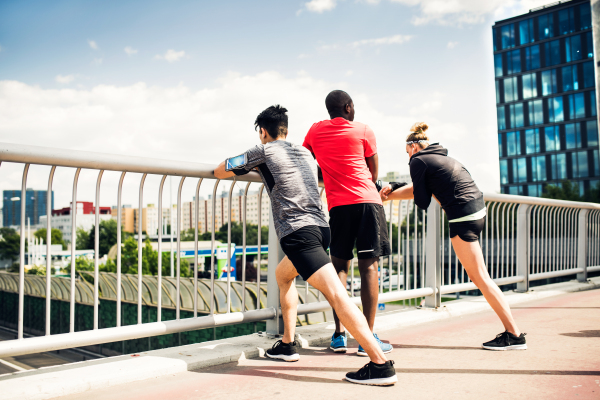 Beautiful young runners in the city on a bridge resting, doing stretching.