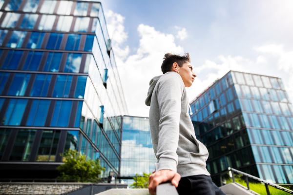 Young runner in the city resting in front of glass buildings.