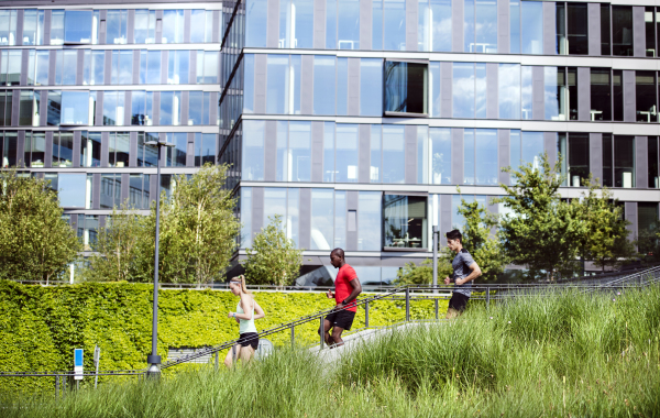 Beautiful young people in the city running together down the stairs in front of glass building.