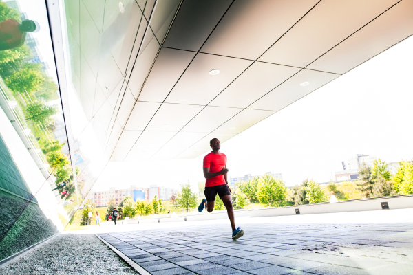 Handsome young afro-american athlete in the city running under the bridge.