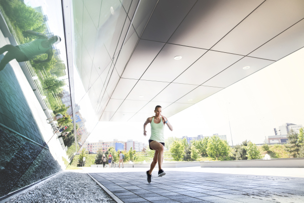 Beautiful young athlete in the city running.