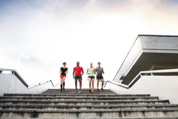 Beautiful young people in the city running together down the stairs.