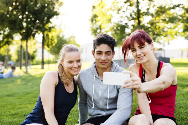 Group of young runners in nature, taking selfie with smartphone.