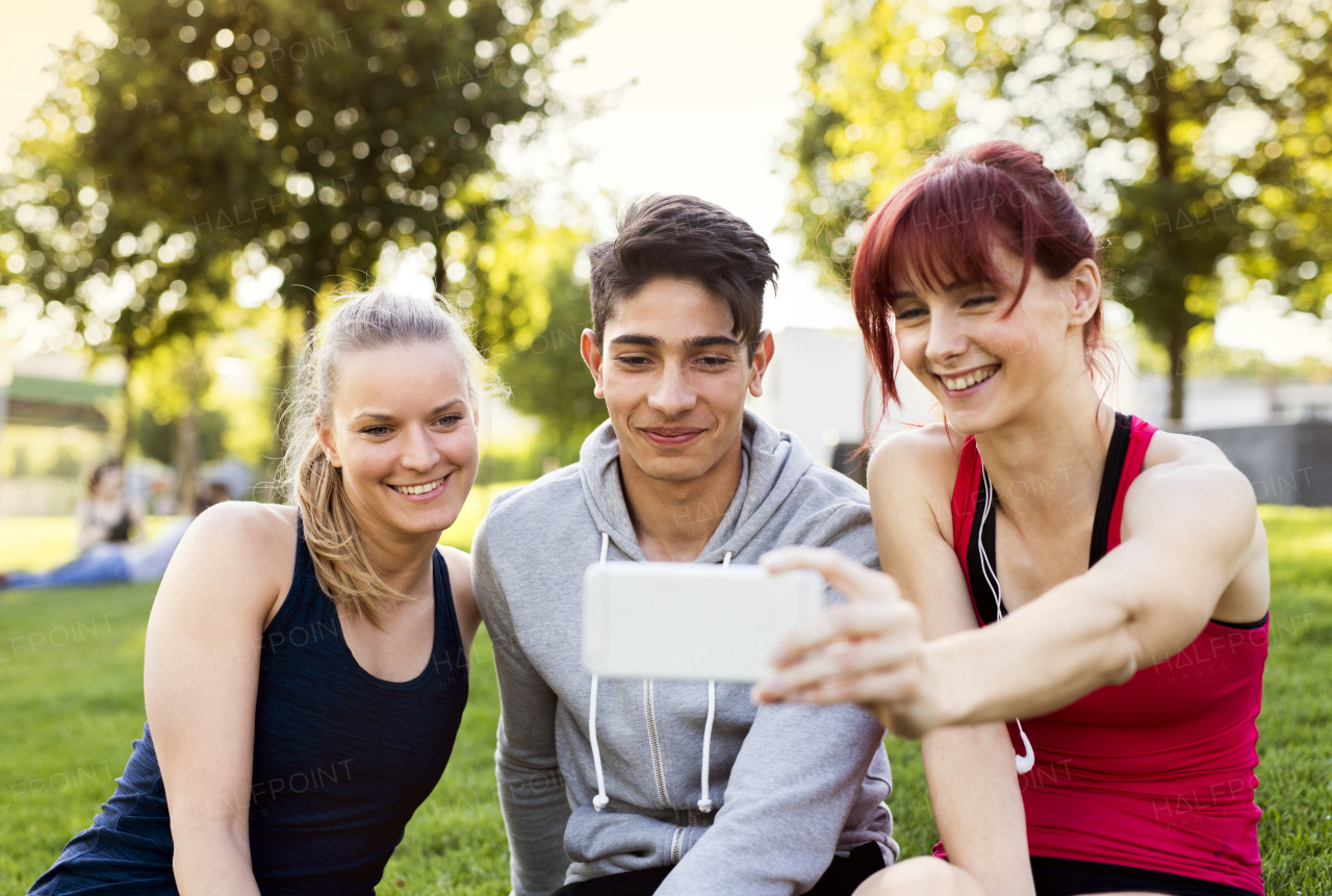 Group of young runners in nature, taking selfie with smartphone.