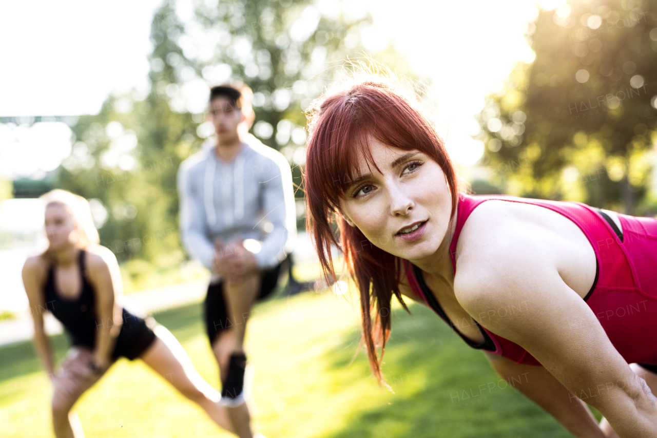 Group of young runners in nature warming up and stretching arms and legs.