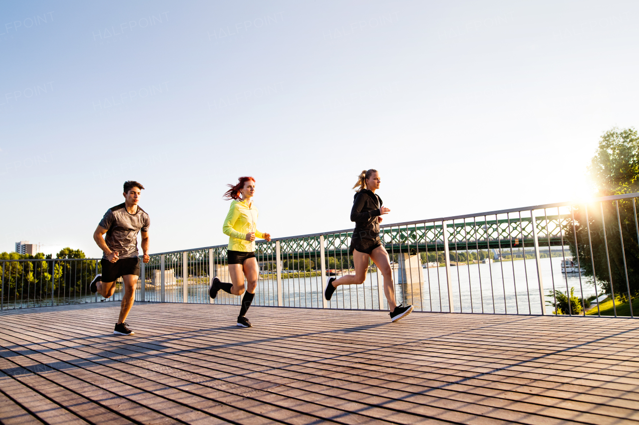 Beautiful young athletes in the city running at the river.