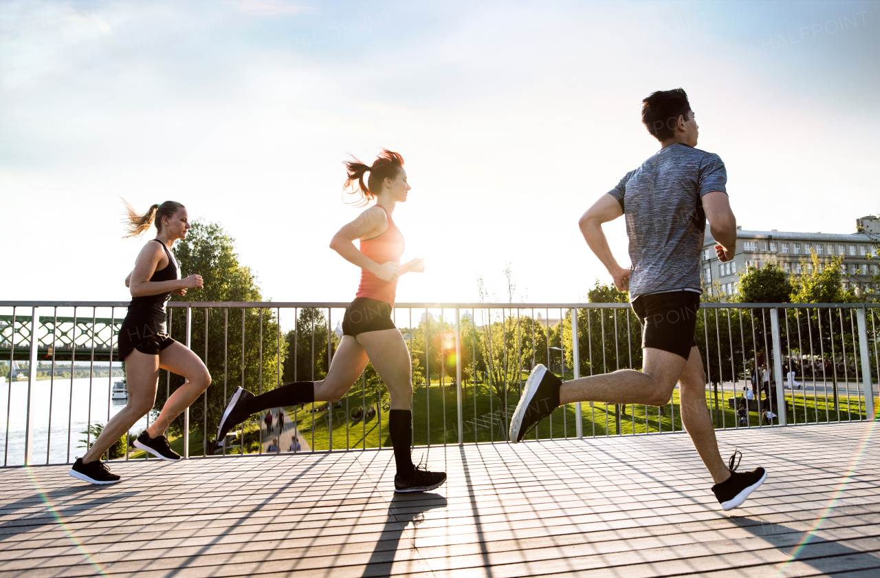 Beautiful young athletes in the city running at the river.