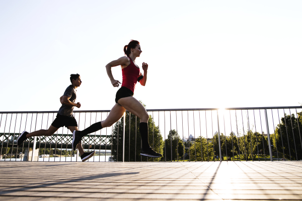 Beautiful young athletes in the city running at the river.