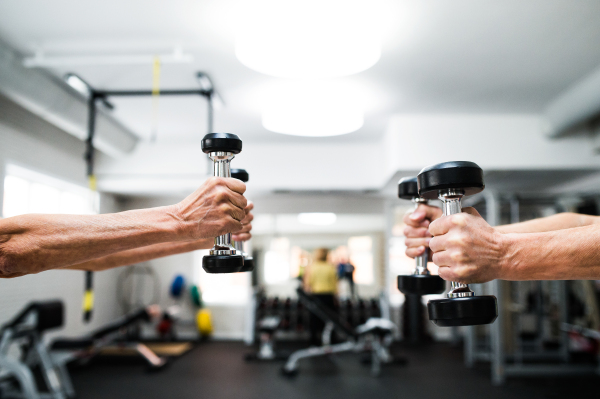 Close up of hands of senior couple in gym working out with weights