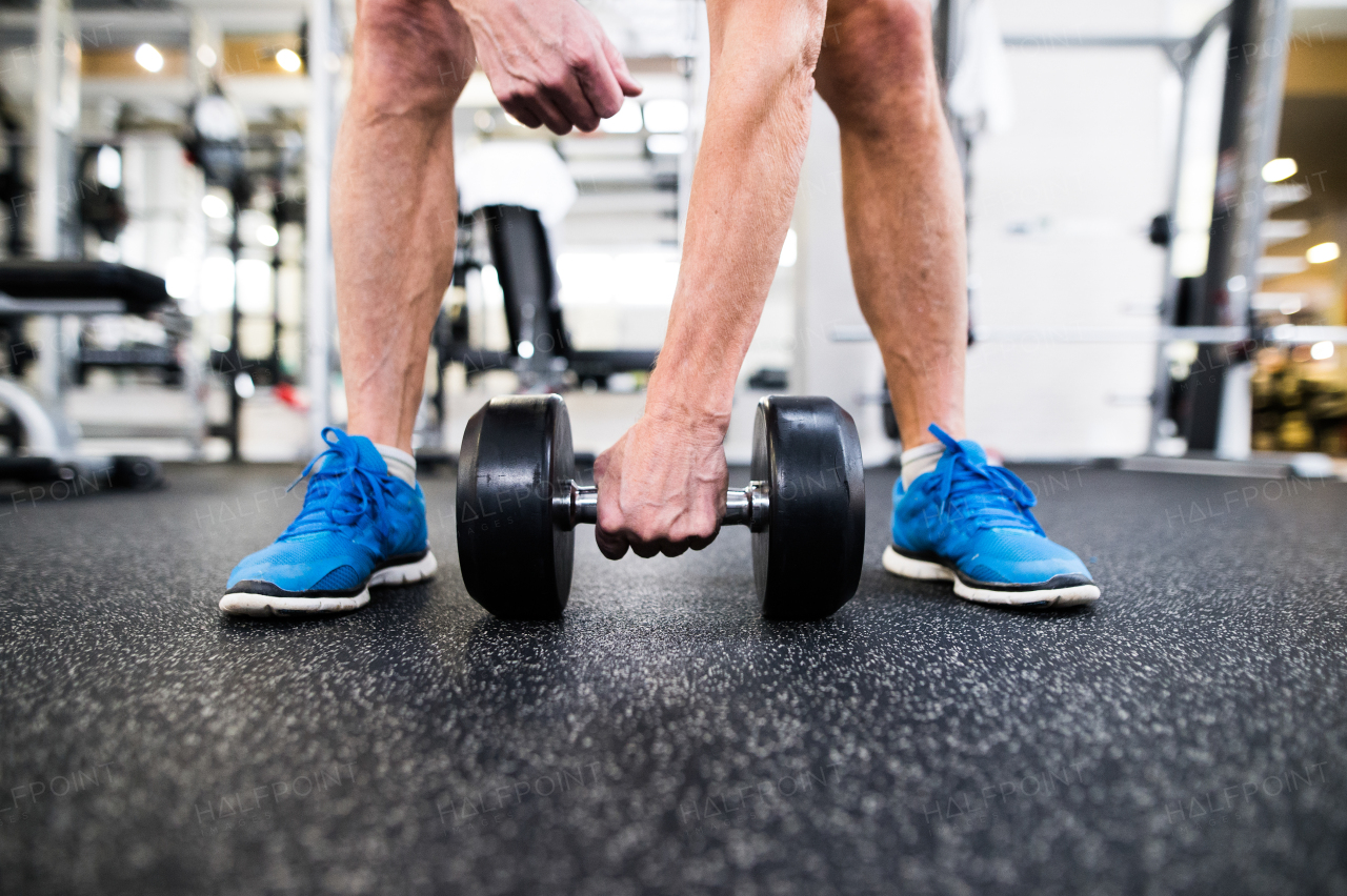 Close up of arm and legs of senior man in gym working out with weights