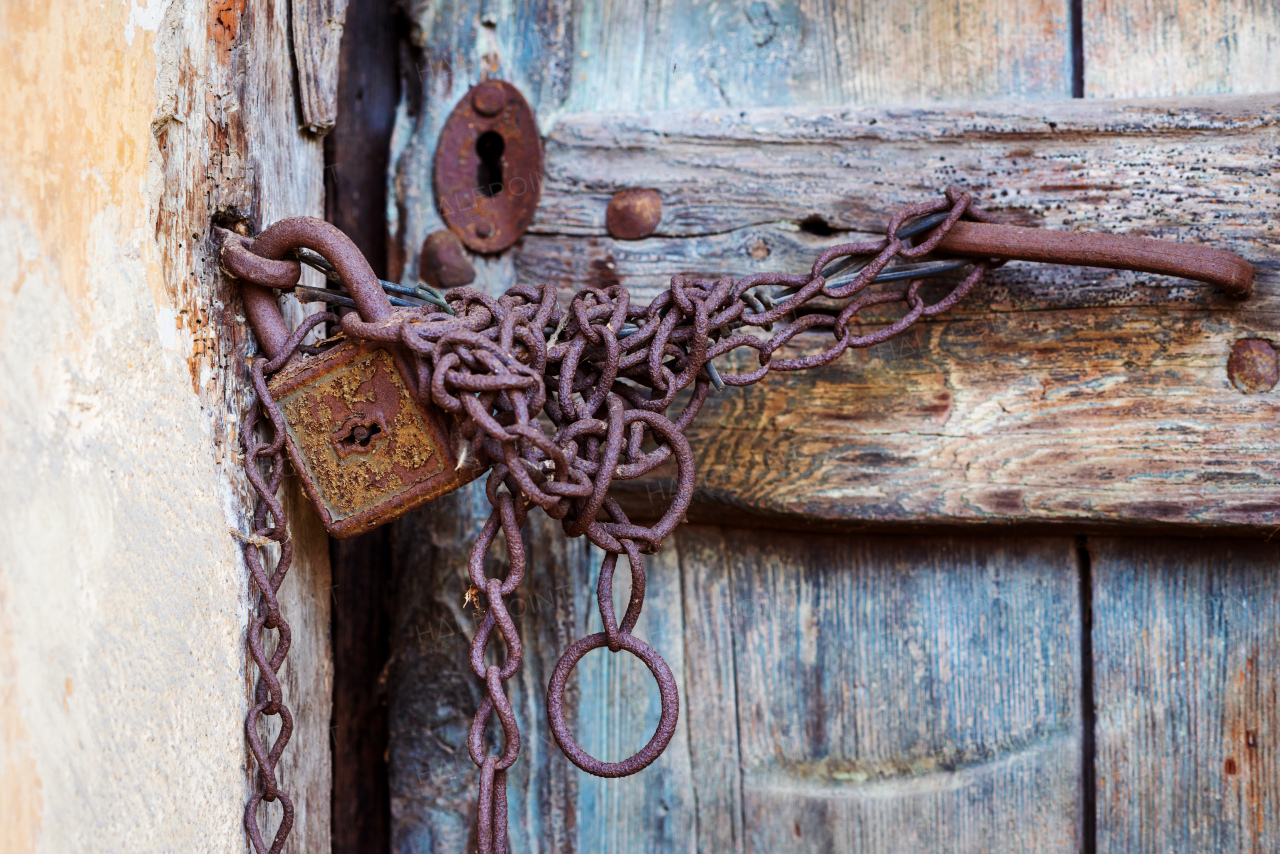 Rusty vintage door lock and chain on an old brown wooden door