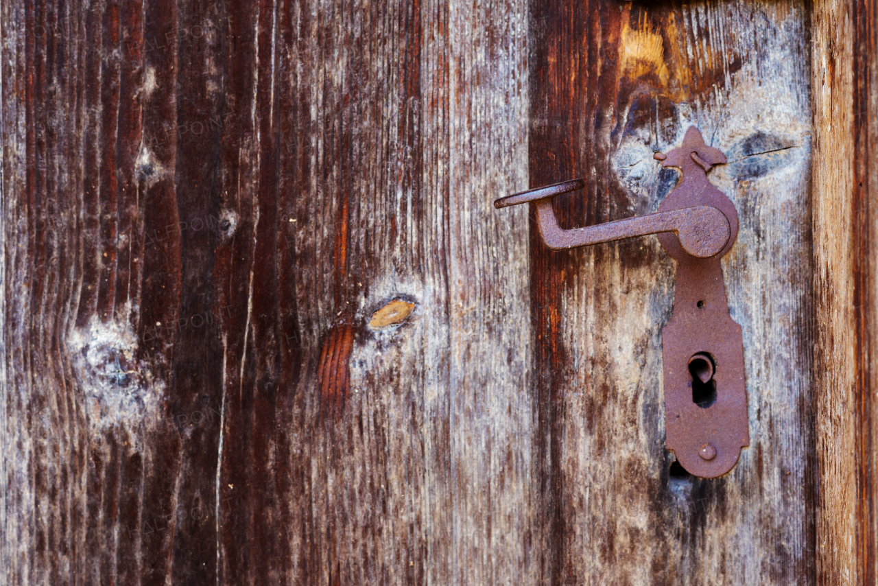 Rusty vintage door handle on an old brown wooden door