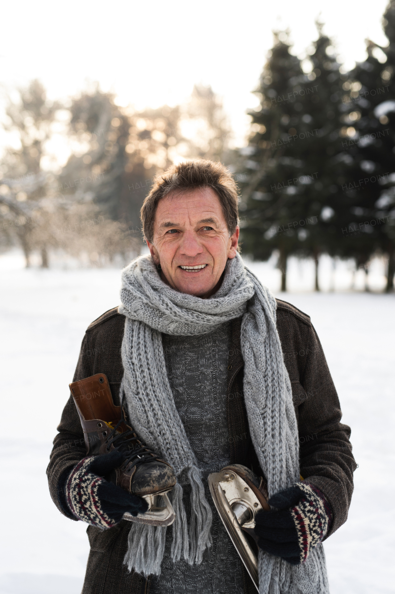 Handsome senior man in sunny winter nature going ice skating.