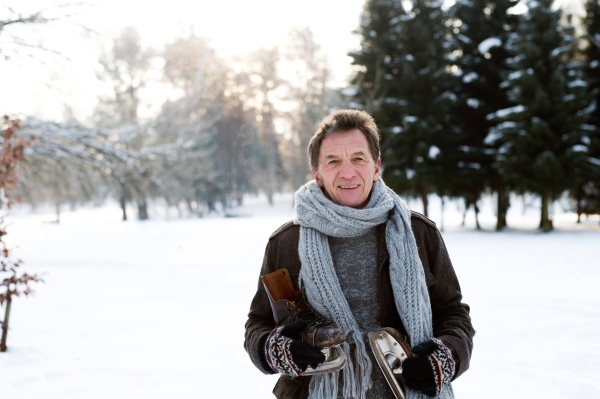 Handsome senior man in sunny winter nature going ice skating.