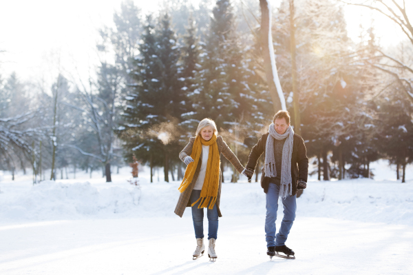 Beautiful senior woman and man in sunny winter nature ice skating.