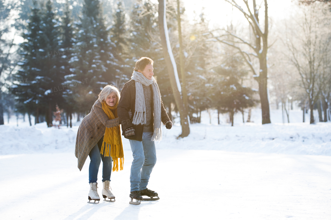 Beautiful senior woman and man in sunny winter nature ice skating.