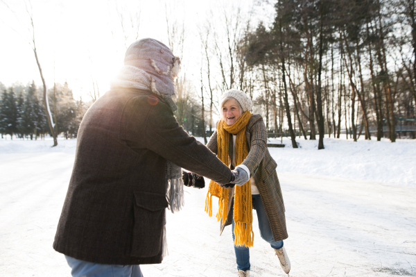 Beautiful senior woman and man in sunny winter nature ice skating.