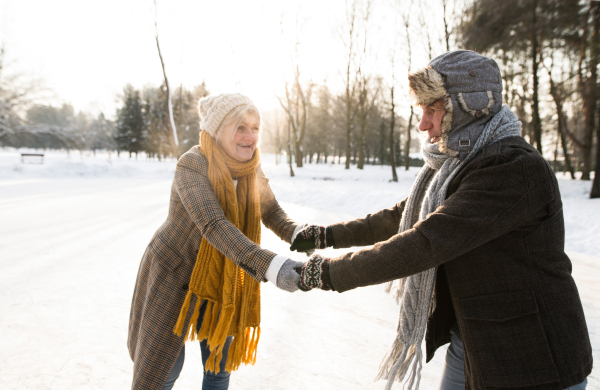 Beautiful senior woman and man in sunny winter nature ice skating.