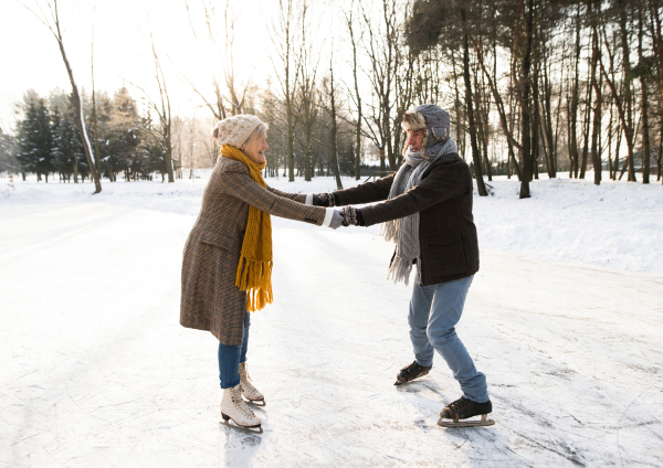 Beautiful senior woman and man in sunny winter nature ice skating.