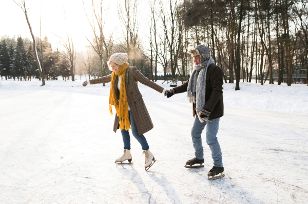 Beautiful senior woman and man in sunny winter nature ice skating.