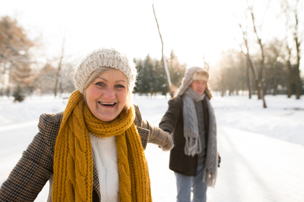 Beautiful senior woman and man in sunny winter nature on a walk, enjoying themselves.