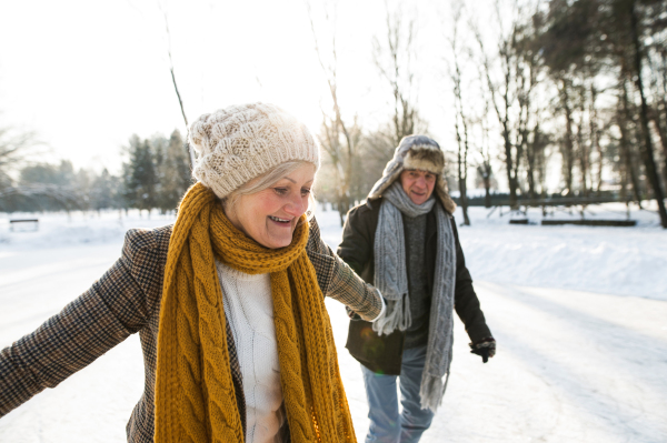 Beautiful senior woman and man in sunny winter nature ice skating.