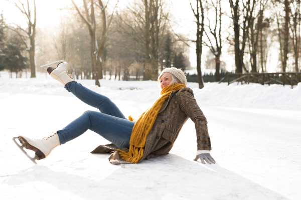 Beautiful senior woman in sunny winter nature. Woman on the ice after a fall.