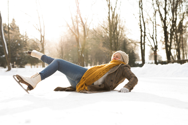 Beautiful senior woman in sunny winter nature. Woman on the ice after a fall.