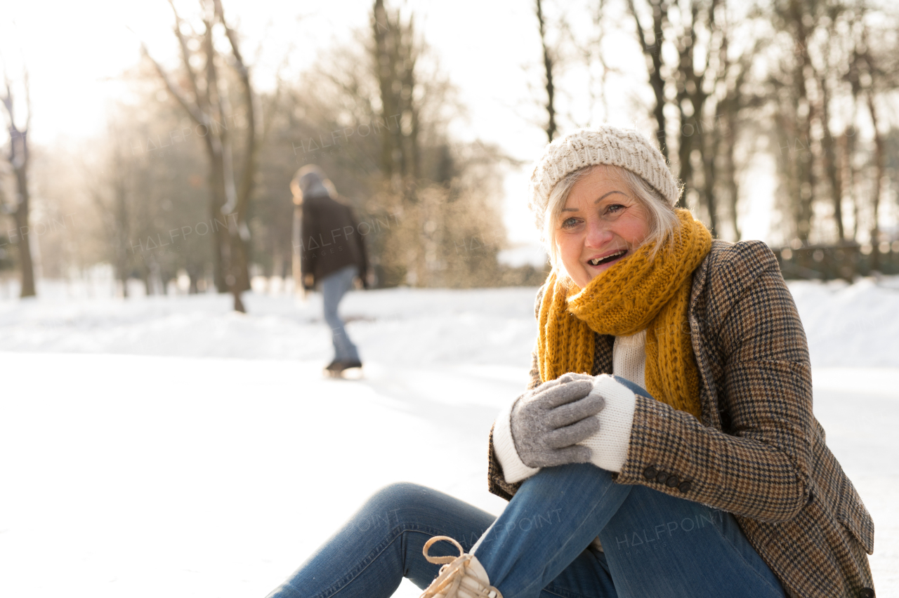 Beautiful senior woman with her husband in sunny winter nature ice skating.