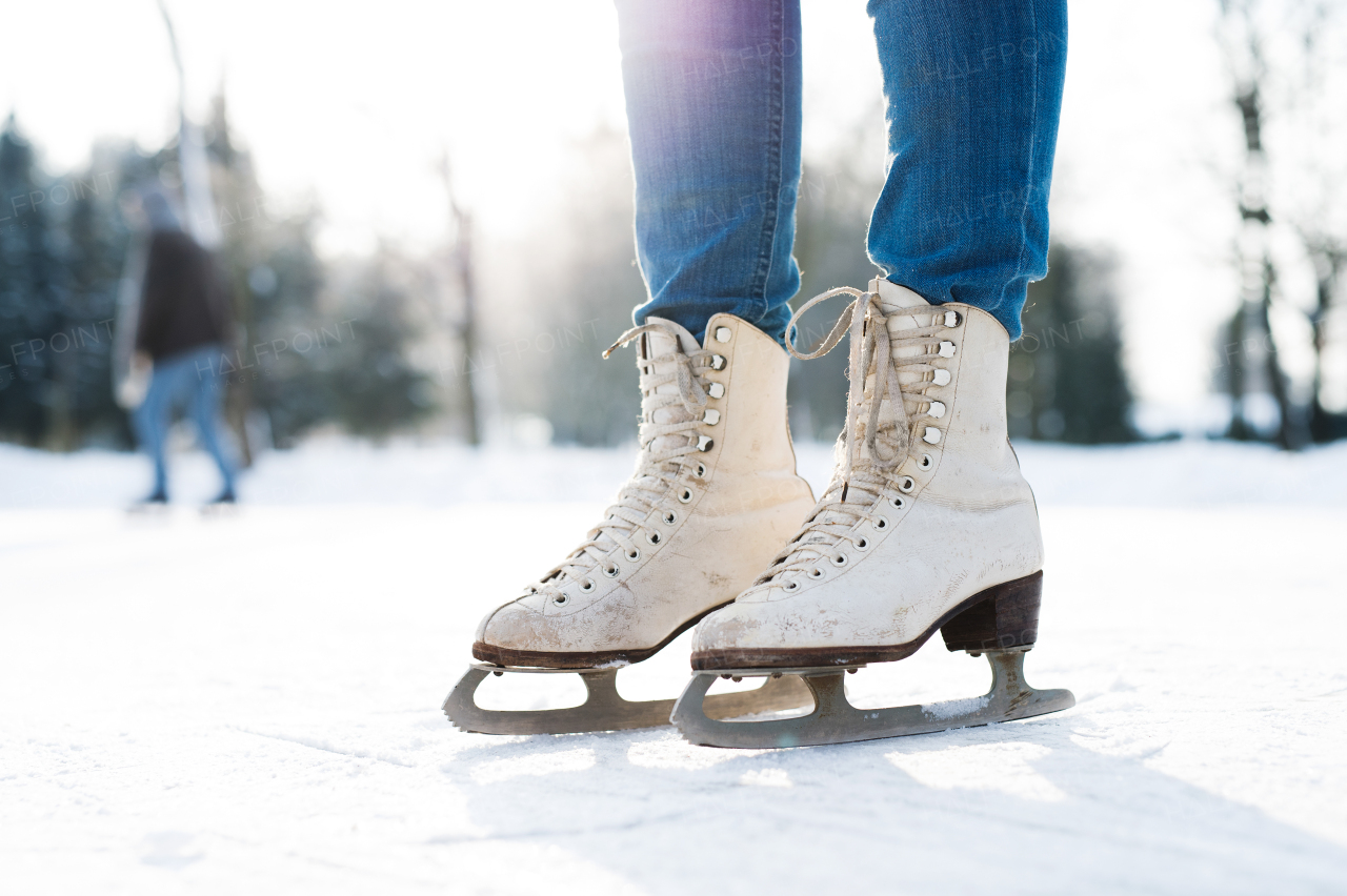 Legs of unrecognizable woman in sunny winter nature ice skating, close up.