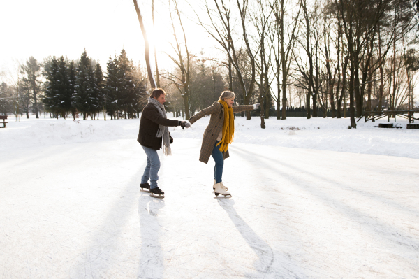 Beautiful senior woman and man in sunny winter nature ice skating.