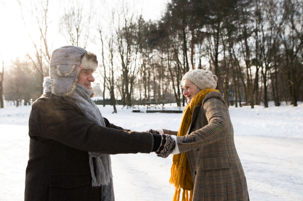 Beautiful senior woman and man in sunny winter nature ice skating.