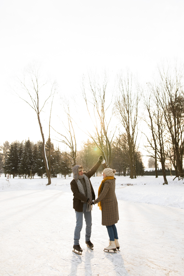 Beautiful senior woman and man in sunny winter nature ice skating.