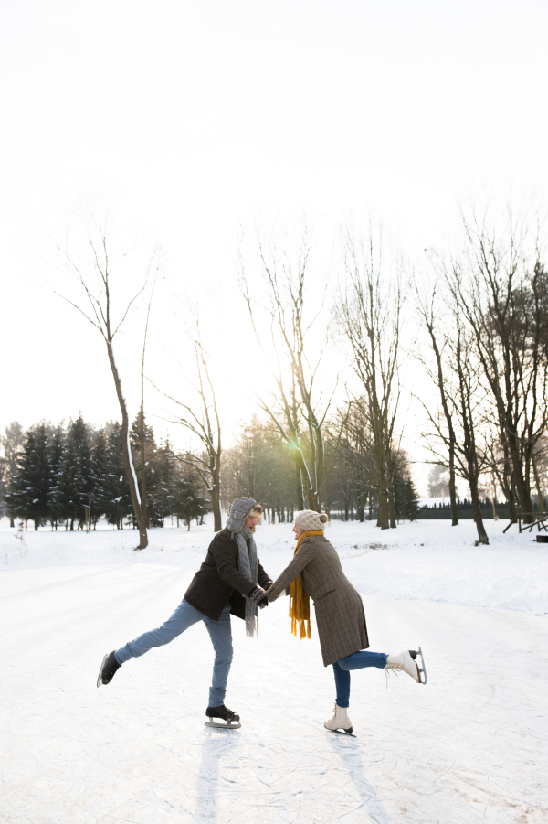 Beautiful senior woman and man in sunny winter nature ice skating.