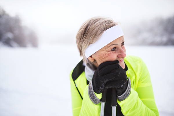 Active senior woman skiing, having a break. Winter time.