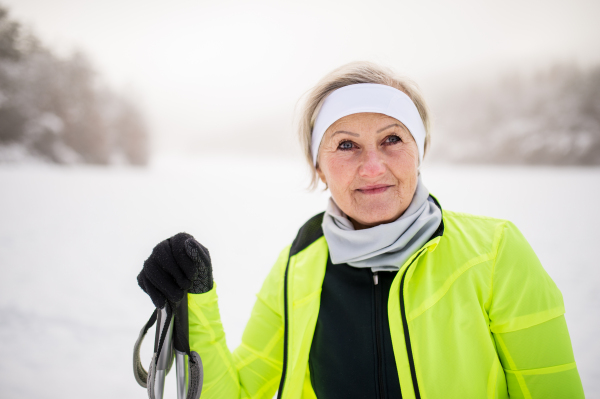 Portrait of an active senior woman skiing, having a break. Winter time.