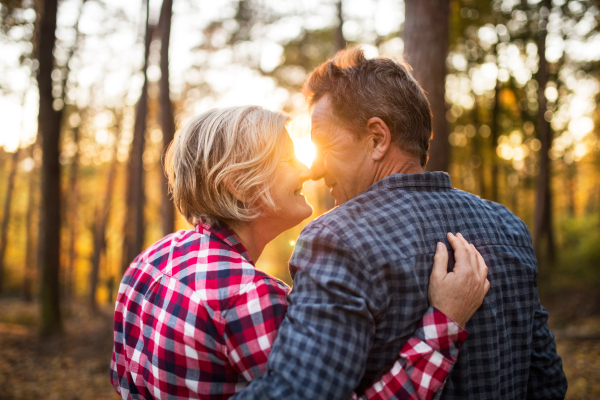 Active senior couple on a walk in a beautiful autumn forest, hugging.