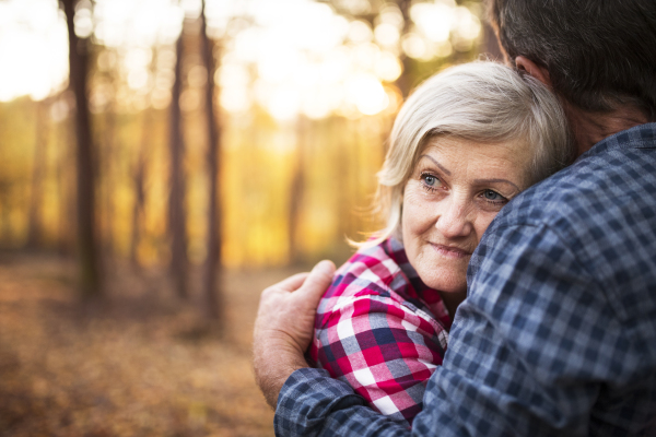 Active senior couple on a walk in a beautiful autumn forest. Unrecognizable man and woman hugging.