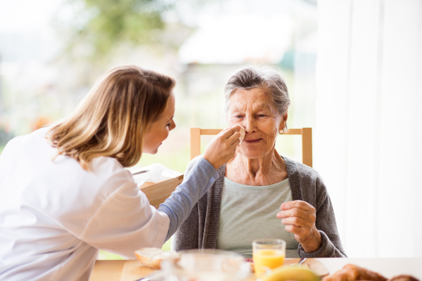 Health visitor and a senior woman during home visit. A nurse and an elderly woman sitting at the table.