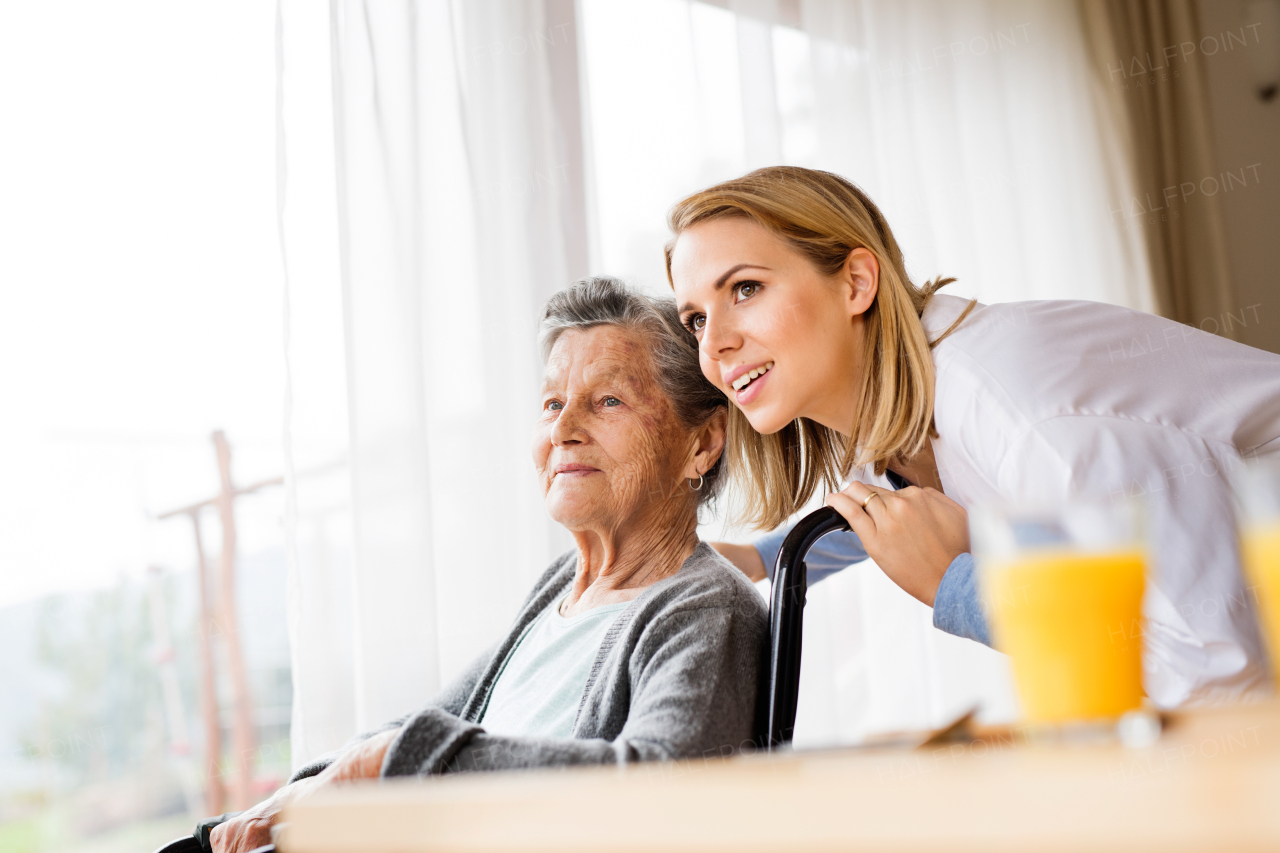 Health visitor and a senior woman during home visit. A nurse talking to an elderly woman in an wheelchair.