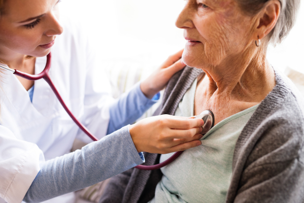 Health visitor and a senior woman during home visit. A nurse or a doctor examining a woman. Close up.