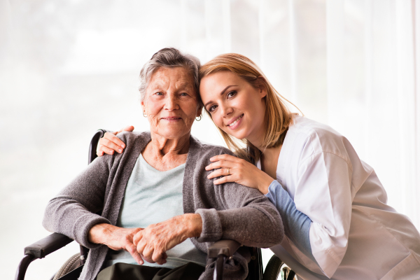 Health visitor and a senior woman during home visit. Portrait of a nurse and an elderly woman in an wheelchair.